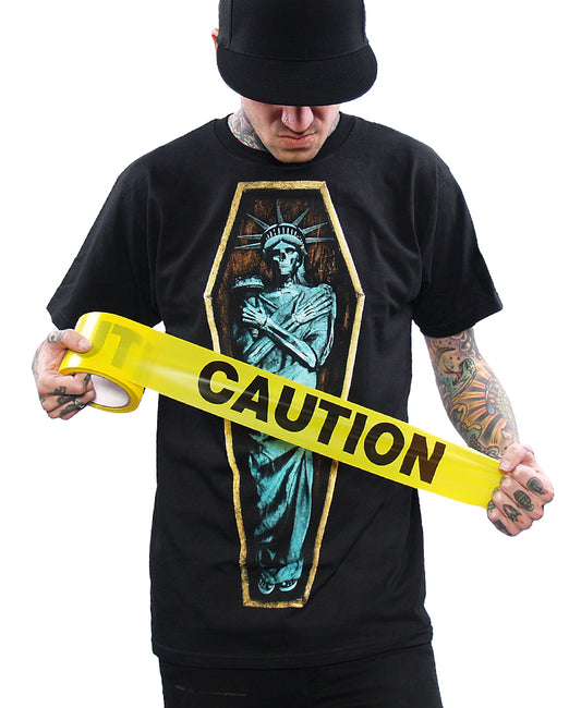 shirt with liberty in coffin model holding caution tape roll