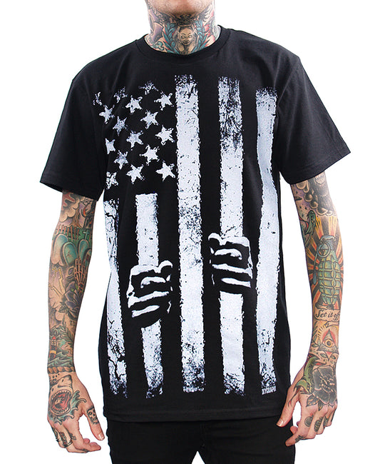 model wearing shirt with american flag and hands holding stripes like in jail