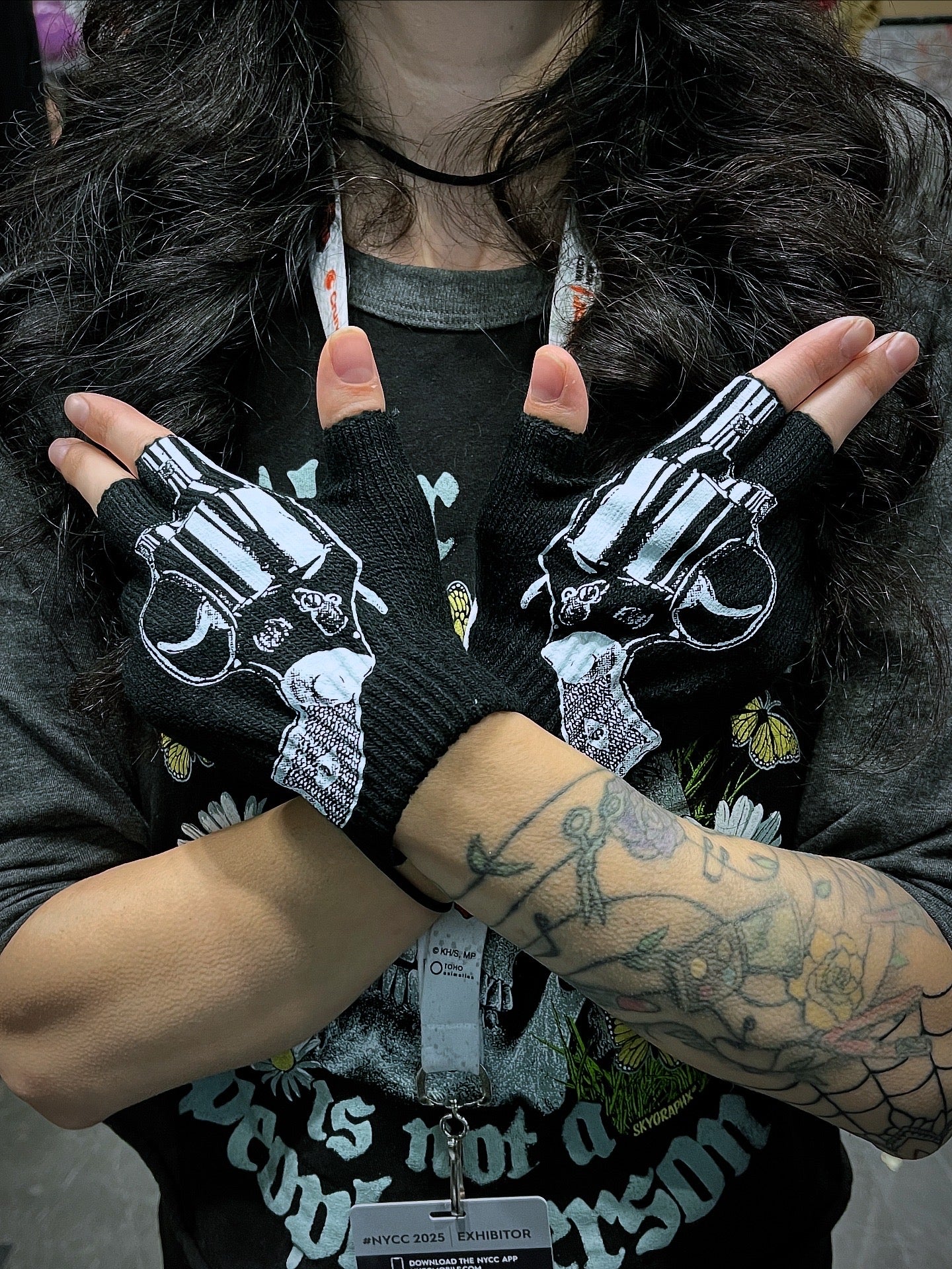 Person wearing black gloves with gun designs, holding hands together.